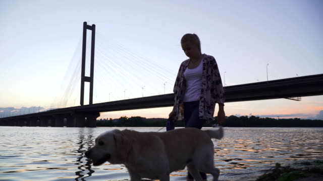 Beautiful-girl-walks-with-a-dog-along-the-river