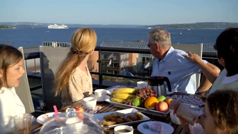 Una-gran-familia-feliz-cena-en-la-terraza-abierta-y-agita-sus-manos-pasando-por-el-ferry-mar