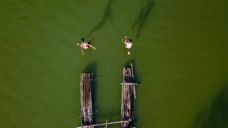 Aerial-view-of-Boys-jumping-into-water-in-lake-at-sunset,-joyful-in-countryside-life-concept