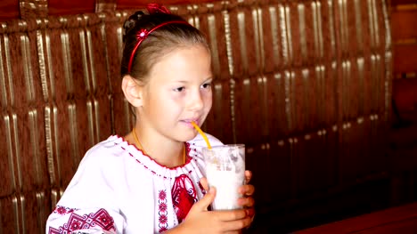 happy-smiling-teen-girl-child-drinks-a-milkshake-in-cafe.-she-is-dressed-in-Ukrainian-national-clothes,-embroidery,-vishivanka