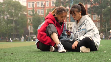 Zwei-glückliche-Asiatinnen-in-Campus-sprechen