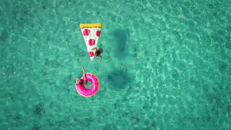 Luftaufnahme-von-zwei-jungen-Mädchen-schwimmen-und-spielen-im-Meer-mit-Hüpfburgen-zu-schließen.
