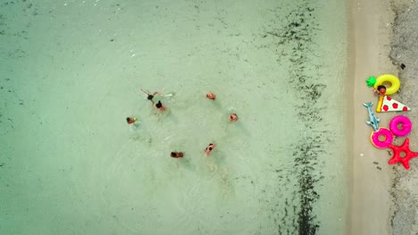 Luftaufnahme-von-Freunden-spielen-Volleyball-stehen-im-Meer-mit-Sandstrand.