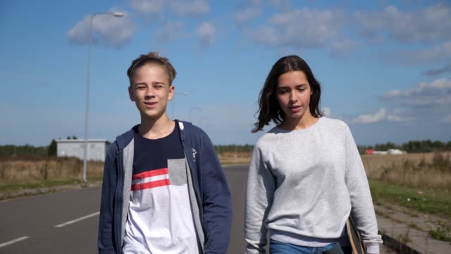 two-young-teenagers-walking-and-talking,-smiling