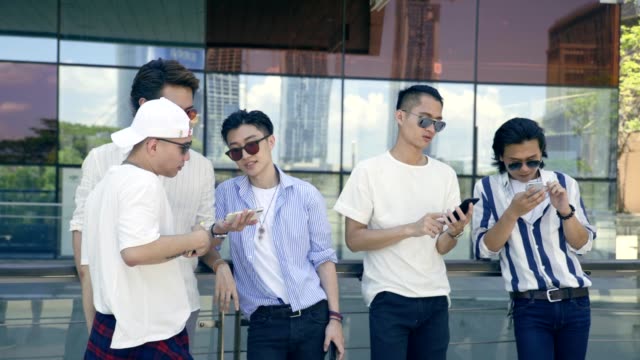Asia-adultos-jóvenes-colgando-hacia-fuera-en-la-calle-mirando-teléfono-móvil