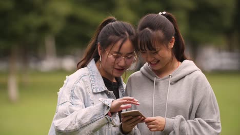 Two-asian-college-girl-using-mobile-phone-in-campus
