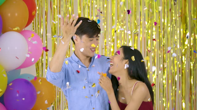 Young-asian-couple-enjoy-with-confetti-over-gold-glitter-background,-slow-motion.
