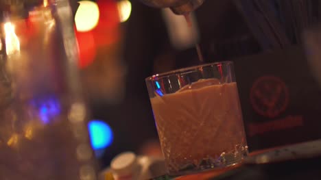 Cocktail-aus-einem-Shaker-in-ein-Glas-gießen