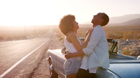 Young-couple-leaning-on-their-car-embracing-at-the-roadside