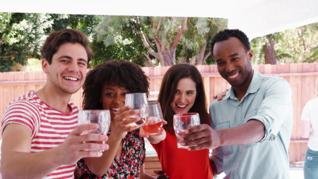 Adult-friends-at-a-backyard-party-raising-glasses-to-camera