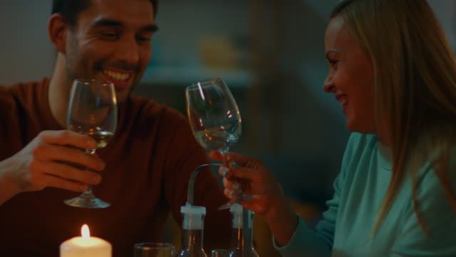 Schöne-junge-Paar-am-Abend-Tisch-schauen-einander-liebevoll-und-Klirren-der-Gläser-in-einem-Toast.-Hintergrund-ist-die-romantische-Kerze-beleuchtet-Atmhosphere.