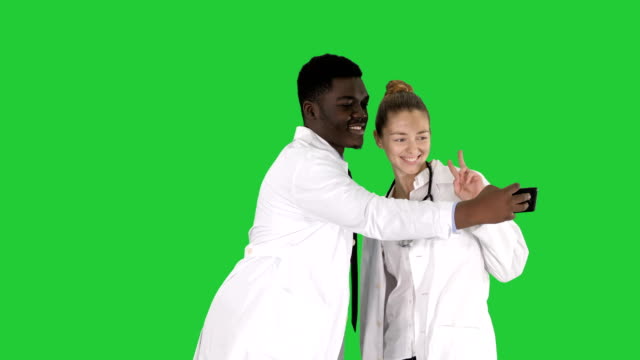 Two-doctors-are-making-selfie-using-a-smartphone-and-smiling-on-a-Green-Screen,-Chroma-Key