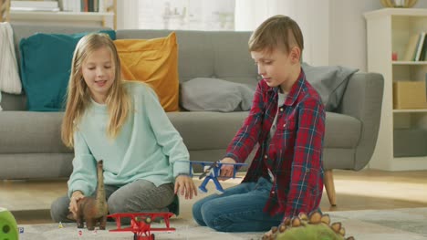 In-the-Living-Room:-Boy-and-Girl-Playing-with-Toy-Airplanes-and-Dinosaurs-while-Sitting-on-a-Carpet.-Sunny-Living-Room-with-Children-Having-Fun.