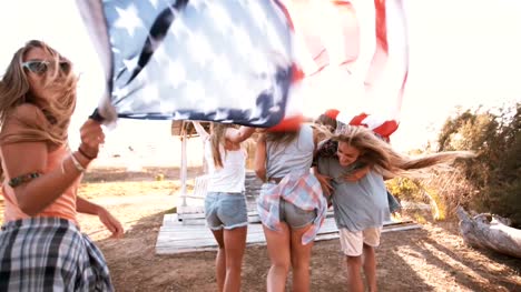 American-adolescentes-caminando-con-bandera-en-resplandor-solar
