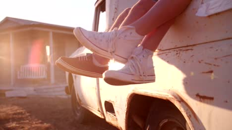 Teen-couple's-legs-hanging-out-of-vehicle-with-sun-flare