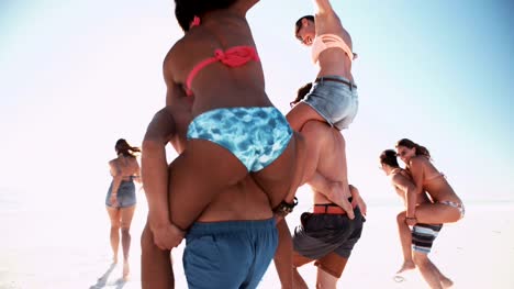 Friends-having-piggyback-races-on-a-beach-in-summer