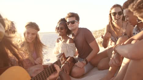 Freunde-auf-einer-sunset-beachparty-mit-einer-Gitarre