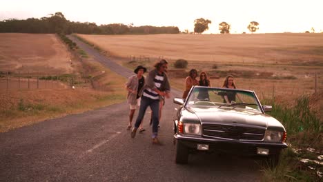 Teenager-friends-running-outside-at-sunset-to-their-car