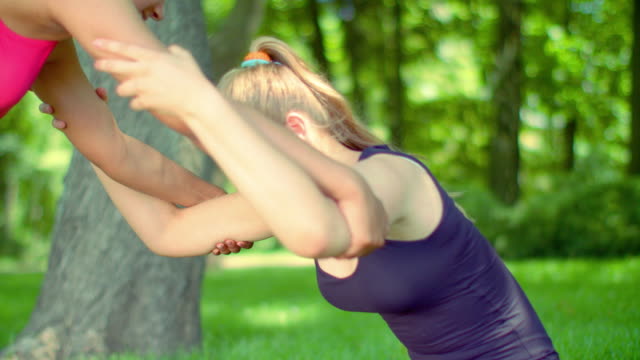 Blonde-woman-stretching-with-help-of-friend-outdoor.-Sport-woman-stretching