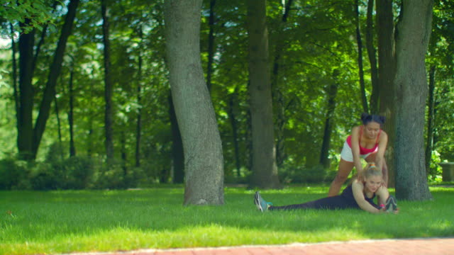Mujer-fitness-hacer-ejercicio-que-estira-en-la-hierba-verde-en-el-Parque