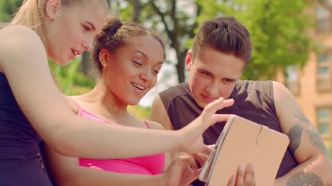Young-people-watching-photo-on-tablet-outdoor.-Young-friends-having-fun