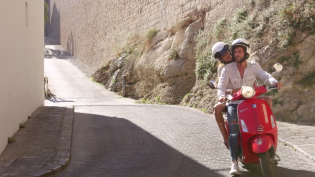 Pareja-joven-montado-en-una-scooter,-Ibiza,-España,-tiro-de-R3D