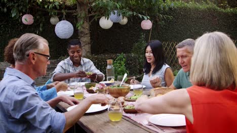 Ältere-Freunde-genießen-Mahlzeit-im-Freien-im-Hinterhof-erschossen-auf-R3D