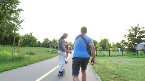 Woman-and-two-men-skateboarding-on-cycling-pathway-at-sunset