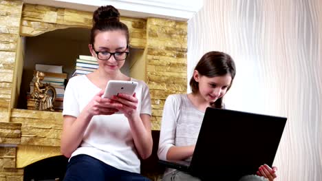 portrait-of-two-pretty-young-girls-using-gadgets-at-home,-friends-socializing-at-home-with-devices