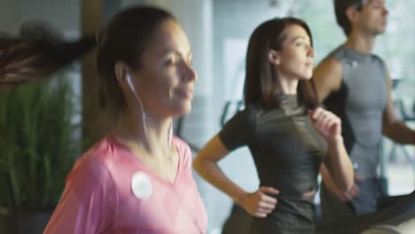 Slow-Motion-Aufnahmen-von-attraktiven-Kaukasische-Mädchen-laufen-auf-dem-Laufband-im-Fitnessstudio-Sport-mit-Kopfhörern.