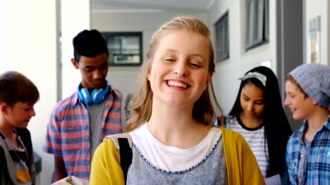 Porträt-des-Lächelns-Schulmädchen-stehend-mit-Notebook-im-Korridor
