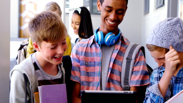 Studierende-mit-Notebooks-und-digitale-Tablet-im-Korridor-stehen