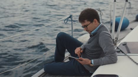 Der-Mensch-nutzt-Tablet-auf-einer-Yacht-in-das-Meer.