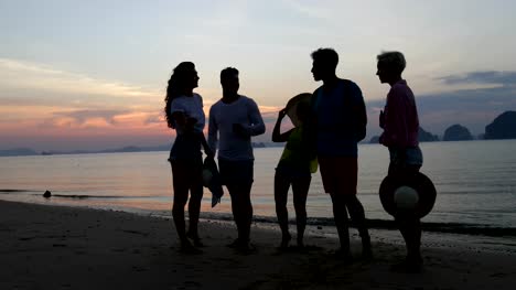 Menschen,-die-am-Strand-im-Sonnenuntergang-reden,-Gruppenkommunikation-junger-Touristen