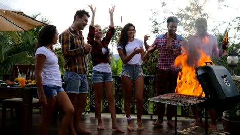 Junge-Menschen-fröhlich-Kochen-Barbecue-glücklich-Frineds-Gruppe-Raise-Hände-treffen-auf-Sommerterrasse-mit-Party