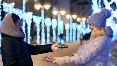 Two-girls-gives-a-presents-to-each-other-at-night-lights-background
