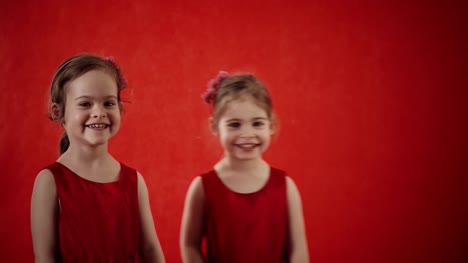 Zwei-kleine-Mädchen-umarmt-auf-rotem-Grund