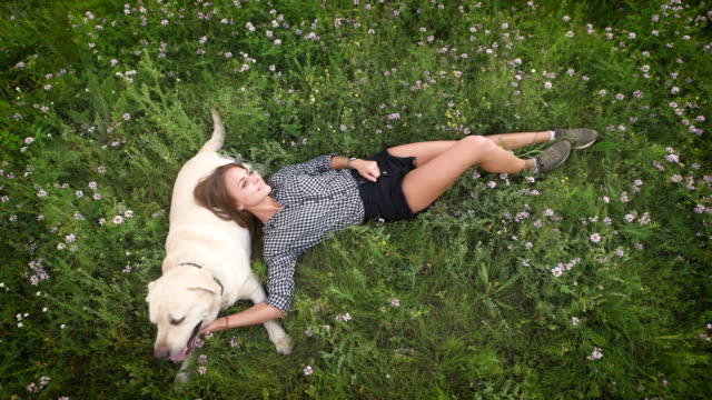 Lustige-Frau-lag-auf-den-Rasen-und-spielt-mit-dem-Hund