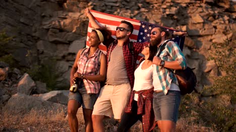 Excited-friends-posing-among-rocks-with-flag