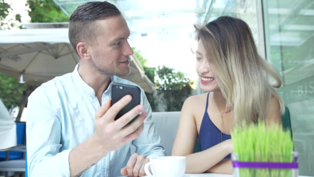 Mixed-race-couple-looking-photos-together-on-smartphone