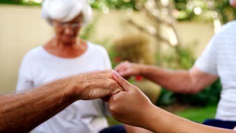 Senioren-Freunde-Hand-in-Hand-und-meditieren-im-Garten-4k