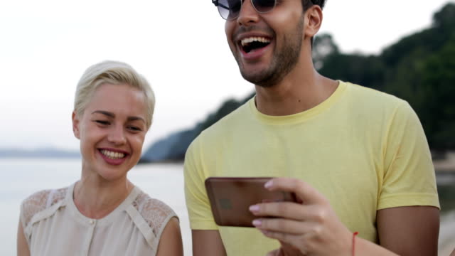 Personas-en-la-playa-hablando-usando-Smart-teléfonos,-jóvenes-turistas-grupo-celular-red-risa-Online