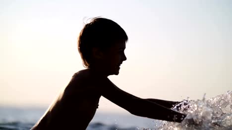 niño-jugando-en-el-mar-con-el-agua-al-atardecer,-salpicaduras