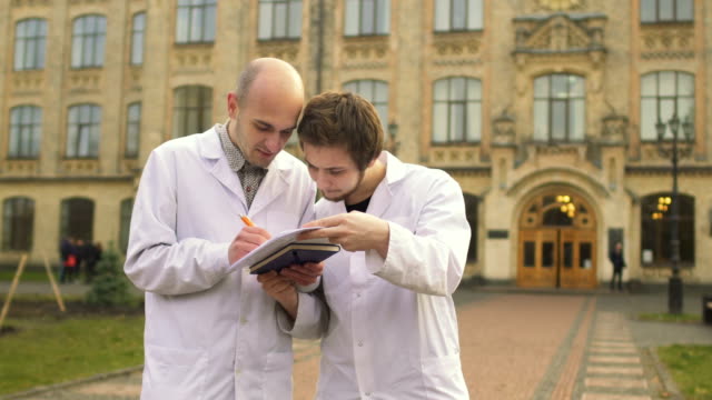 Zwei-Medizinstudenten-im-Bademantel-am-Campus-Hintergrund-etwas-zu-besprechen