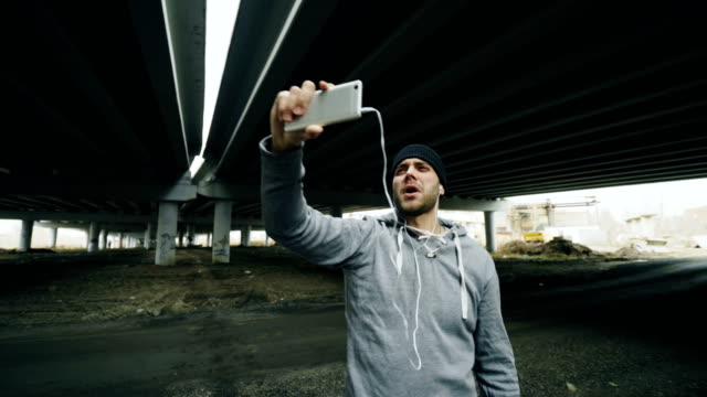 Athlete-man-having-video-chat-on-smartphone-with-his-trainer-after-workout-at-urban-location-outdoors-in-winter