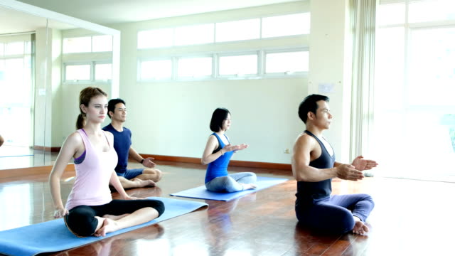 Gruppe-junger-Menschen,-die-Yoga-in-der-Klasse-zu-tun.