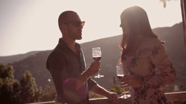 Junges-Paar-Wein-trinken-auf-rustikalen-Balkon-mit-Bergblick
