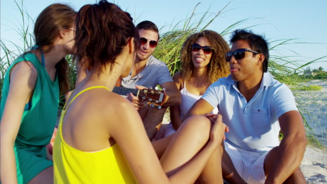 Multi-ethnic-friends-relaxing-with-picnic-on-beach