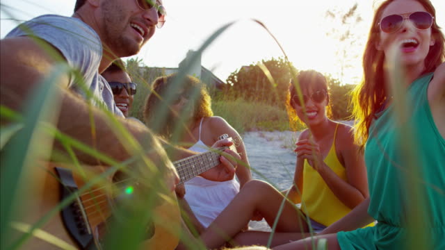 Jóvenes-multi-étnica-amigos-disfrutar-de-picnic-en-la-playa