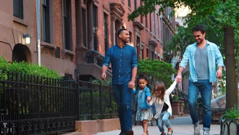 Zwei-Väter-und-ihre-Töchter-Fuß-in-der-Straße-reden